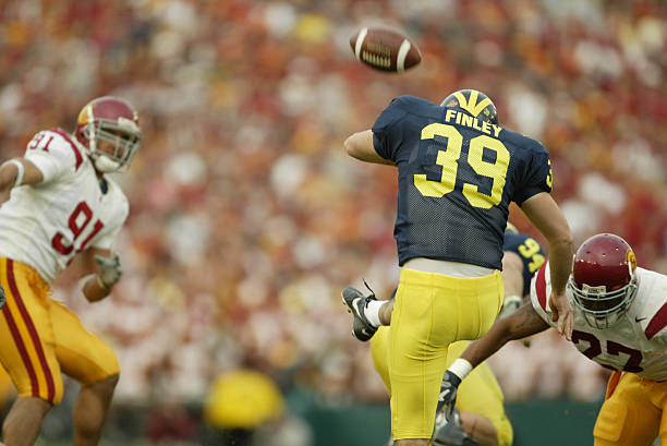 jan-2004-adam-finley-of-the-michigan-wolverines-just-gets-a-punt-away-picture-id110330083